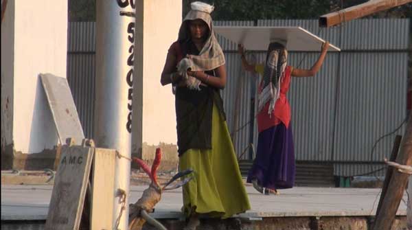 Women carrying construction materials on high-rise construction site.